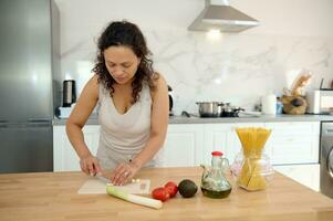 femme au foyer couper Ail sur Coupe conseil, en train de préparer une en bonne santé salade de mûr biologique des légumes dans le Accueil cuisine photo