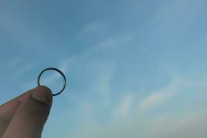 argent bague dans le main sur le bleu ciel Contexte photo