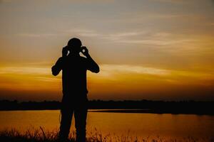 Masculin touristes permanent par le téléthon à le coucher du soleil. photo