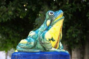 une grenouille statue sur une bleu et Jaune piédestal photo