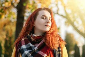 portrait de Jeune roux femme sur ensoleillé l'automne journée. Dame avec fermé yeux profiter Soleil. photo
