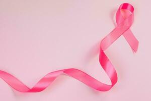 ruban rose sur fond coloré. symbole du mois de sensibilisation au cancer du sein. concept de soins de santé des femmes. promotion de la campagne de lutte contre le cancer. photo