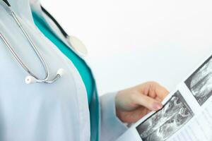 femme médecin dans blanc médical manteau avec stéthoscope détient résultats de ultrason analyse dans sa mains. infirmière dans hôpital. santé se soucier concept photo