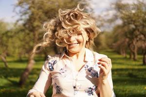 heureuse jeune femme aux cheveux blonds, vêtue d'une robe, posant à l'extérieur photo