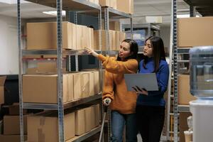 entrepôt ouvriers choisir papier carton boîte à préparer client commande pour expédition. entrepôt asiatique femmes employé sur béquilles Faire inventaire la gestion avec superviseur dans espace de rangement pièce photo