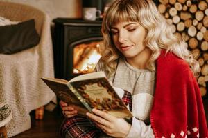 Happy young woman reading book devant l'intérieur de Noël photo