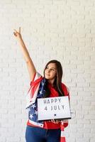 femme avec un drapeau américain tenant une lightbox avec des mots heureux 4 juillet photo