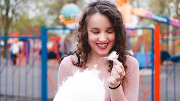 fille excitée souriante tenant une barbe à papa au parc d'attractions photo