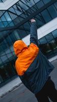 Jeune homme en uniforme de travail orange - bâtiment en verre sur l'arrière-plan photo