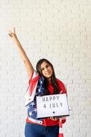 femme avec un drapeau américain tenant une lightbox avec des mots heureux 4 juillet photo