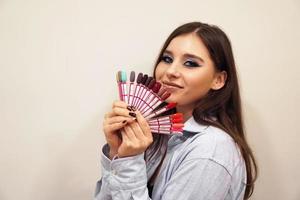 femme souriante, tenant une palette de vernis à ongles manucure et pédicure photo