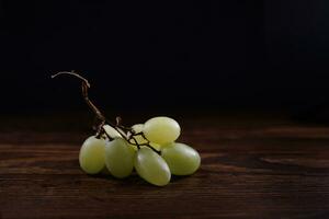 une petit bouquet de mûr vert les raisins sur une en bois planche. photo