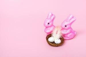 lapins de pâques et un nid avec des oeufs sur fond rose. notion de vacances. gros plan de l'espace de copie photo