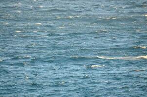 une grand corps de l'eau avec vagues et une bateau dans le milieu photo