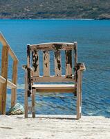 en bois chaise surplombant le bleu mer à pomos port, île de Chypre photo