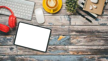 en bois bureau avec Vide écran tablette, clavier, souris, casque de musique, stylo, carnet et tasse de café, Haut vue plat allonger avec copie espace. photo