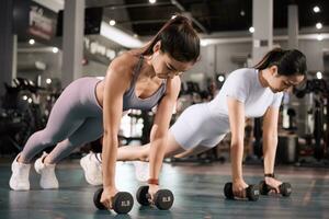 deux Jeune asiatique femme sont travail en dehors avec haltères dans le salle de sport. photo