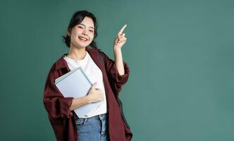 portrait de une magnifique asiatique étudiant sur une vert Contexte photo