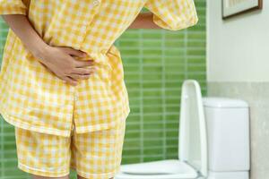 constipation et diarrhée dans la salle de bain. blesser la femme toucher le ventre mal de ventre douloureux. problème d'inflammation du côlon, aliments toxiques, douleurs abdominales, abdomen, toilettes constipées, maux de ventre, hygiène photo