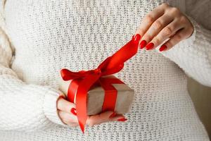 cadeau avec un ruban rouge en mains sur fond blanc photo