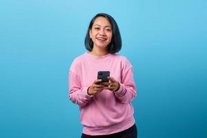 joyeuse jeune femme asiatique tenant un smartphone et heureuse pour l'avenir photo