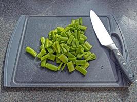 haricots verts hachés avec un couteau de chef sur une planche à découper