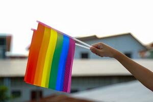 mains en portant arc en ciel drapeaux orner bâtiments comme une symbole de lgbt fierté. doux et sélectif se concentrer. photo