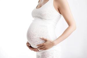 une Enceinte femme détient sa ventre contre une blanc Contexte. photo