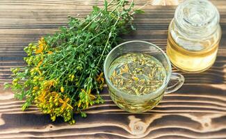 transparent tasse de st. John's moût remède boisson avec bouquet Frais hypericum Jaune fleurs photo