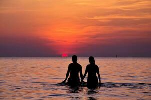 silhouette de couple à le mer à le coucher du soleil photo