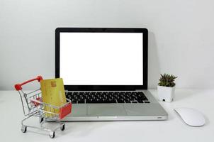 ordinateur portable maquette blanc vierge et chariot et carte de crédit sur le bureau. photo