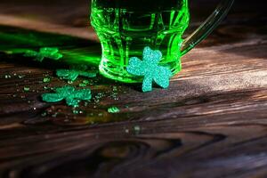 trèfle feuilles avec éclaboussures de du froid Bière sur une en bois tableau. une verre de vert traditionnel Bière sur st. patrick's journée dans un irlandais pub photo