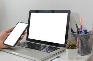 maquette main tenant un ordinateur portable à écran blanc blanc smartphone sur le bureau photo