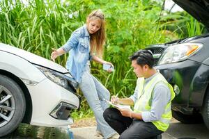 femme Conducteurs dément après le voiture écrasé avec Assurance entreprise officier vérification voiture dégâts sur pays route. photo