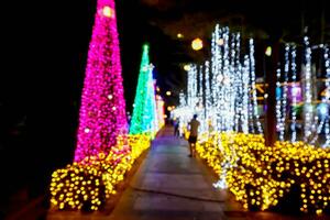 flou et bokeh de Noël vacances éclairage avec gens sur nuit temps Contexte. photo