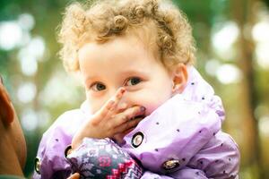 le peu fille détient une main près le affronter. les doigts enfant avec peint clous. content bébé dans le bras de le sien père photo