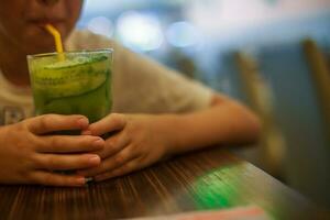 garçon les boissons de pailles jus. enfant en portant une verre de cocktail. photo