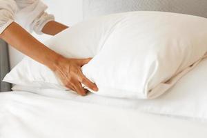 main féminine mis en place un drap de lit blanc dans la chambre photo