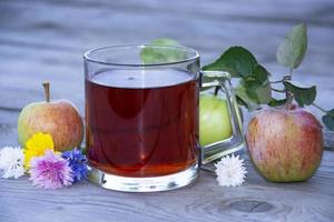 tasse avec du thé parmi les fruits sur un fond en bois. photo