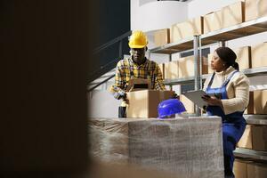 entrepôt paquet gestionnaire et superviseur en train de préparer paquet pour expéditeur. africain américain femme en portant presse-papiers et entrepôt employé portant casque emballage papier carton boîte avec gluant ruban photo