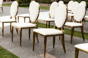 luxe blanc-doré chaises sur mariage la cérémonie en plein air. de fête décorations. vide Lignes les fauteuils pour invités. sortant mariage la cérémonie dans le ouvert air. décor studio. photo