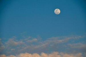 le lune est vu dans le bleu ciel avec des nuages photo