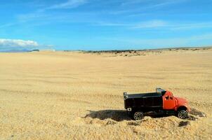 une jouet un camion est séance dans le le sable photo