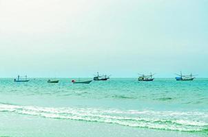 la plage de sable et la mer avec bateau qui stationne sur le front de mer. photo