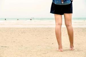 le voyageur se tient sur la plage de sable et regarde les gens nager photo