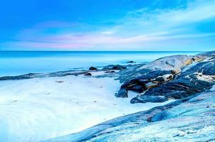 la vue sur la plage de sable et la vague de mer avec rocher et récif le matin photo