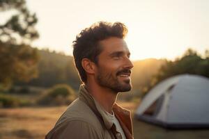 portrait de homme à la recherche à caméra tandis que près camping tente à le coucher du soleil ai généré photo