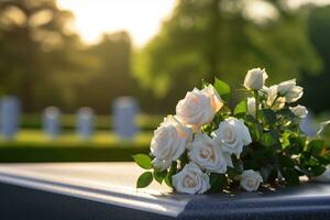 blanc fleurs dans de face de une pierre tombale à une cimetière avec coucher de soleil.funérailles concept ai généré photo