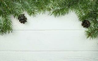 Noël et Nouveau année en bois blanc Contexte avec branches de une Noël arbre, cônes et flocons de neige. hiver Contexte. endroit pour texte. Haut voir. photo