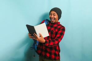 excité Jeune asiatique étudiant est agréablement surpris par une livre il lire, isolé sur bleu Contexte photo